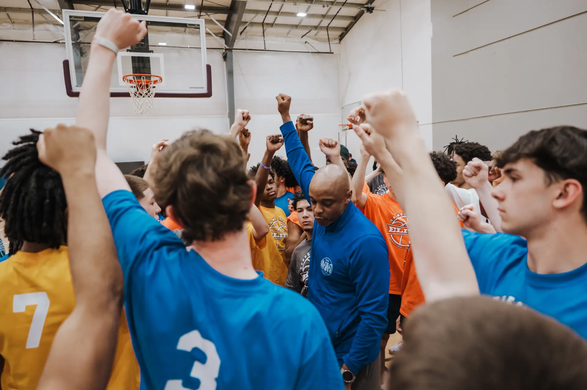 Connecticut Elite coach and players raising fists together in a huddle